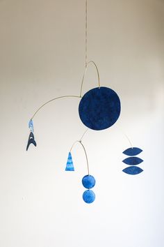 a wind chime hanging from the ceiling with blue circles and shapes on it's sides