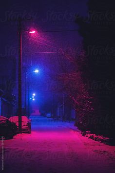 a street light that is lit up in the dark with red lights on it and snow all around