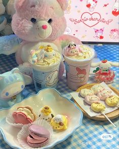 a teddy bear sitting at a table with desserts