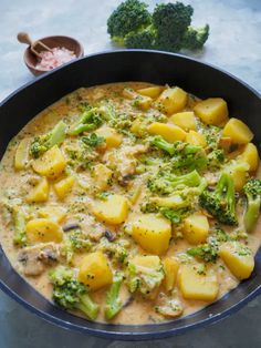 a pan filled with potatoes and broccoli on top of a table