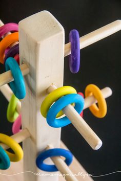 a wooden peg holder with colorful rings on it