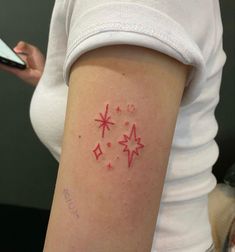 a woman's arm with red ink and stars on the left side of her arm