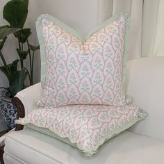 a white couch with two pillows on top of it next to a potted plant