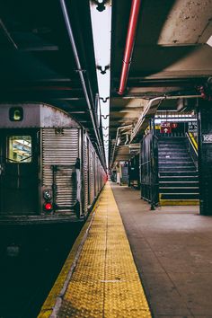 an empty subway station with stairs leading up to the platform