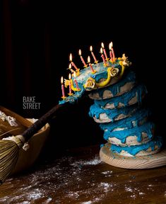 a birthday cake with candles on top of it and a broom in the middle next to it