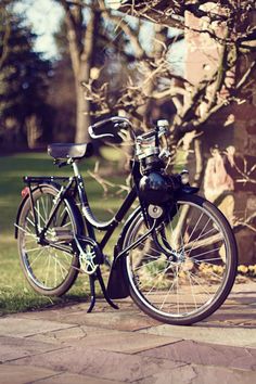 a bike parked on the side of a road next to a tree and grass field