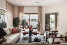 a living room filled with lots of furniture next to a large glass window covered in curtains