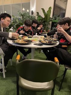 four men sitting at a table eating food