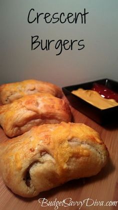 three pastries sitting on top of a wooden table next to a bowl of mustard