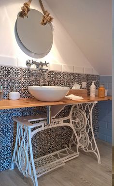 a white sink sitting under a bathroom mirror next to a wooden table with a bowl on it