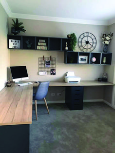 a home office with two desks and a clock on the wall above it's shelves