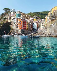 the water is crystal blue and clear with buildings on the hill in the back ground