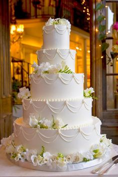 a three tiered white wedding cake sitting on top of a table next to a knife and fork