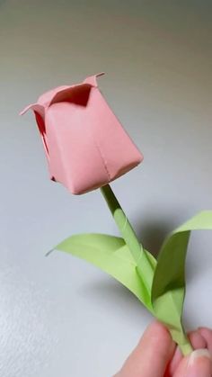 a hand holding a pink origami flower