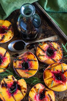 several peaches are sitting on the ground next to a bottle of wine and spoons