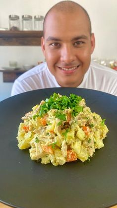 a man sitting in front of a black plate with food on it