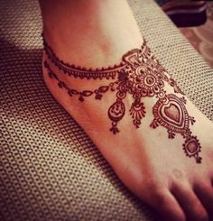 a woman's foot with henna tattoos on it