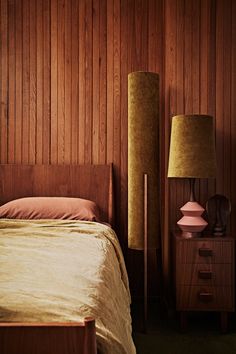 a bed sitting next to a night stand with two lamps on each side of it