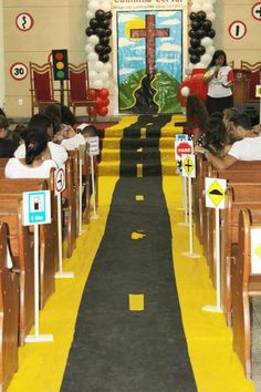 children are sitting in pews at the end of a school hallway decorated with balloons and streamers