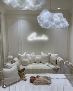 a baby's room is decorated in white and has clouds above the couch