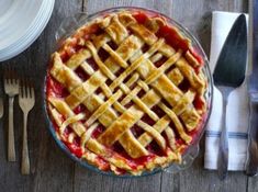 a pie sitting on top of a wooden table next to silverware and utensils