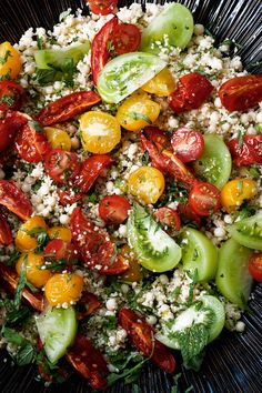 a salad with tomatoes, cucumbers and feta cheese in a black bowl