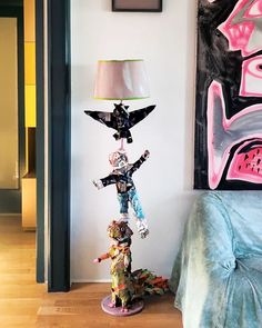 a lamp that is sitting on top of a table next to a painting and a bed