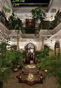 an indoor courtyard with potted plants and lights on the ceiling is lit up at night