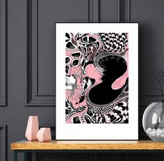 a black and pink abstract art print on a wall next to a vase with flowers