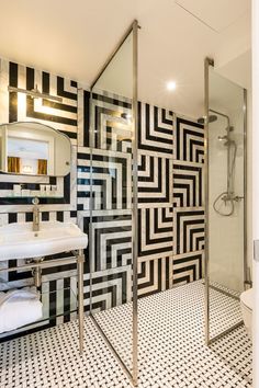 a bathroom with black and white tiles on the walls, flooring and shower stall