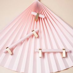 three pink and gold colored objects laying on top of each other in the shape of a fan