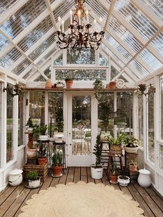 a room filled with lots of potted plants inside of a glass roofed building