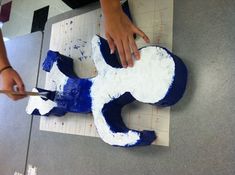 a person cutting up a horse shaped cake on top of a sheet of white paper