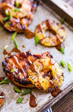 grilled pineapples with bbq sauce and green onions on a baking sheet