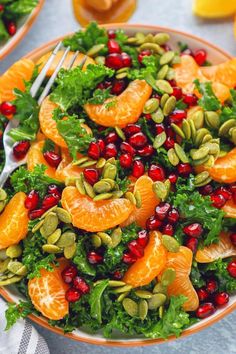 a salad with oranges, cranberries and pistachio seeds on it