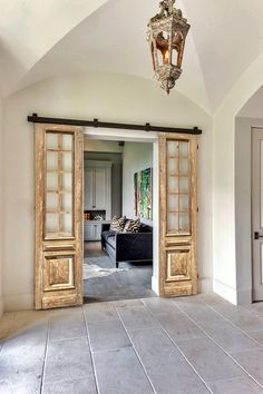 an open door leading to a living room with a couch and chandelier hanging from the ceiling