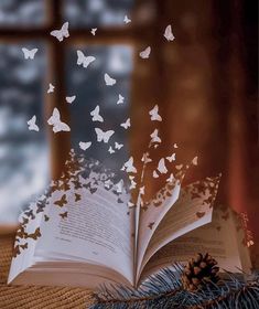 an open book with butterflies flying out of it