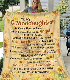 a woman holding up a blanket with the words to her granddaughter on it and sunflowers