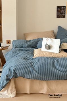 a bed with blue and white striped comforter in a bedroom next to a book shelf