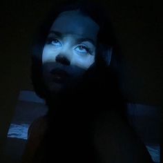 a woman with blue eyes and black hair in the dark