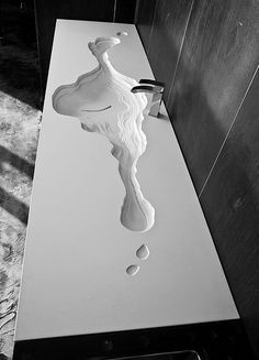 a white sink sitting on top of a counter next to a wooden wall mounted faucet