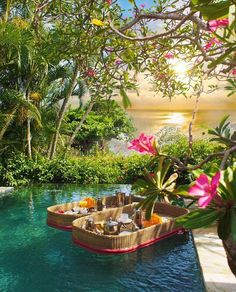 a boat is floating in the middle of a pool with flowers and drinks on it