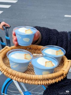 a person holding a basket with four cups on it and a bike in the background