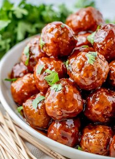 a bowl filled with meatballs covered in sauce and garnished with parsley