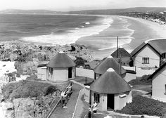 black and white photograph of houses on the beach with ocean in backgroung