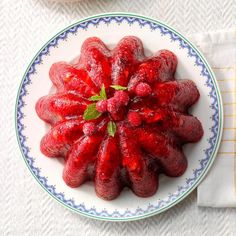 a white plate topped with red fruit on top of a blue and white table cloth