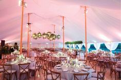 the inside of a large tent with tables and chairs set up for an outdoor function