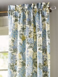 a blue and white flowered curtain hanging on the side of a window sill