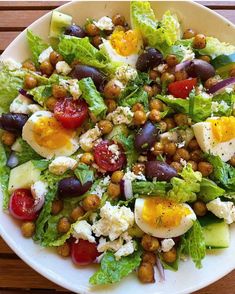 a salad with eggs, tomatoes, lettuce and chickpeas on it