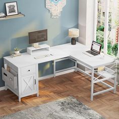 a white desk with drawers and a laptop on it in a blue walled office space